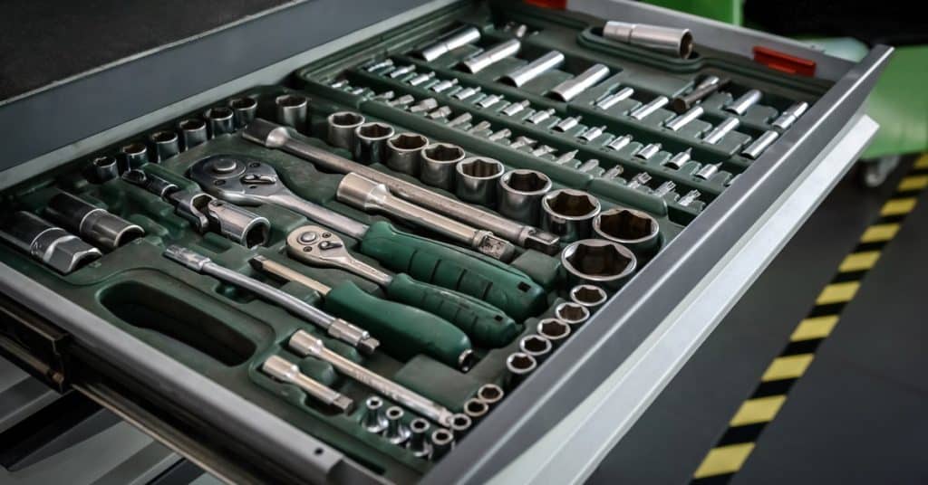 A pulled-out drawer with tools and components lying in different compartments. The drawers beneath them are closed.