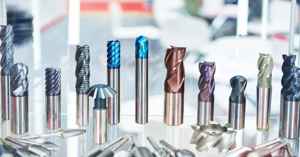 A close-up of cutting tools for a milling machine. The tools have jagged, cylindrical tops with different colors.