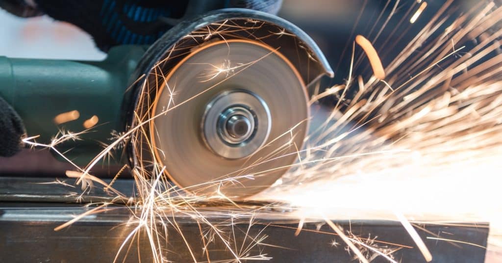 A close-up of someone using a metal cutting tool to cut material. Numerous sparks fly near the material.