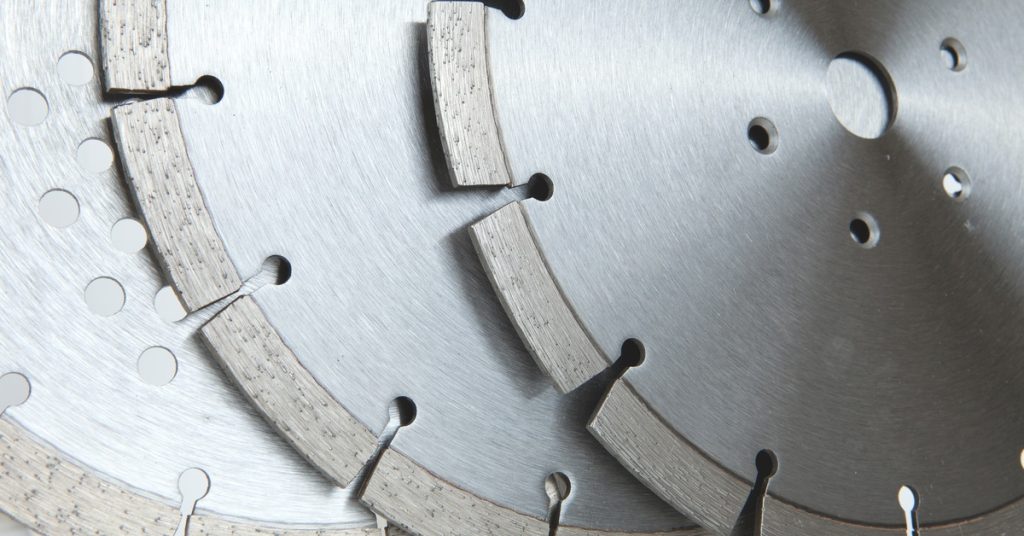 A close-up of diamond-coated cutting discs leaning on each other. The discs have holes on the surface and edges.